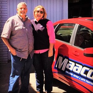 Woman and man standing next to Maaco branded car posing.